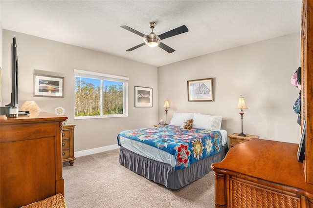 bedroom with ceiling fan, light carpet, and a textured ceiling