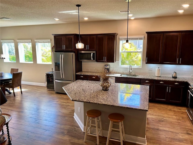 kitchen featuring light wood-style floors, appliances with stainless steel finishes, backsplash, and a sink