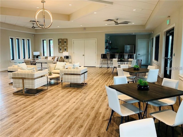 living area with recessed lighting, a raised ceiling, a ceiling fan, wood finished floors, and baseboards