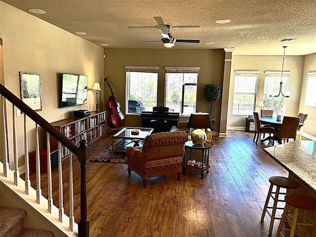 living area with stairway, visible vents, a wealth of natural light, and dark wood-type flooring