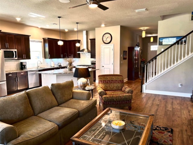 living room with baseboards, dark wood finished floors, a ceiling fan, stairway, and a textured ceiling