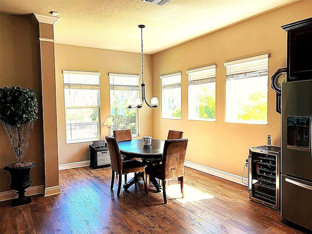 dining area featuring a textured ceiling, wine cooler, dark wood-type flooring, and baseboards