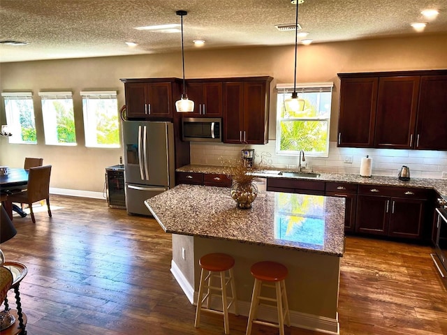 kitchen featuring appliances with stainless steel finishes, backsplash, a sink, and dark wood finished floors