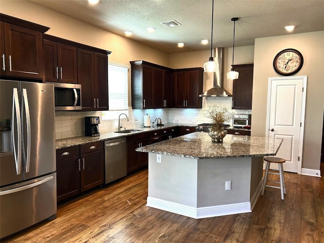 kitchen featuring a breakfast bar area, stainless steel appliances, dark wood-type flooring, a sink, and dark stone counters