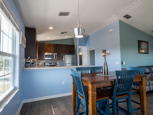 dining space with dark wood-type flooring and vaulted ceiling