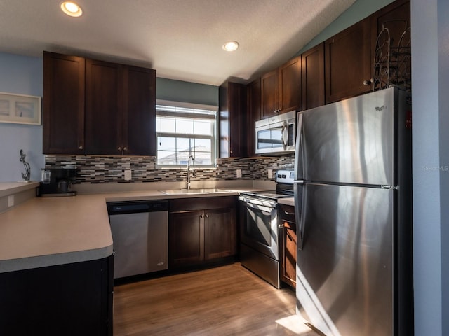 kitchen featuring light wood-type flooring, stainless steel appliances, dark brown cabinetry, and sink