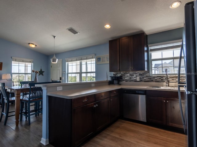 kitchen with dishwasher, kitchen peninsula, sink, and a wealth of natural light