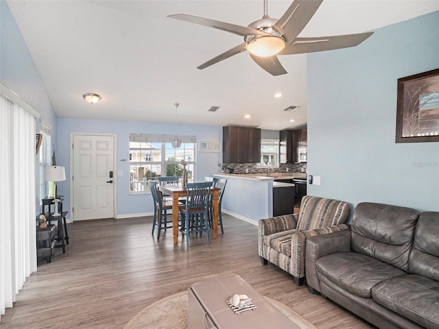 living room featuring ceiling fan, light hardwood / wood-style flooring, and vaulted ceiling