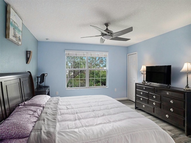 bedroom with a textured ceiling, light wood-type flooring, a closet, and ceiling fan