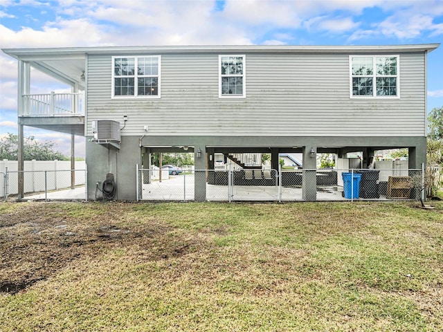 back of house with a lawn, central air condition unit, a balcony, and a carport