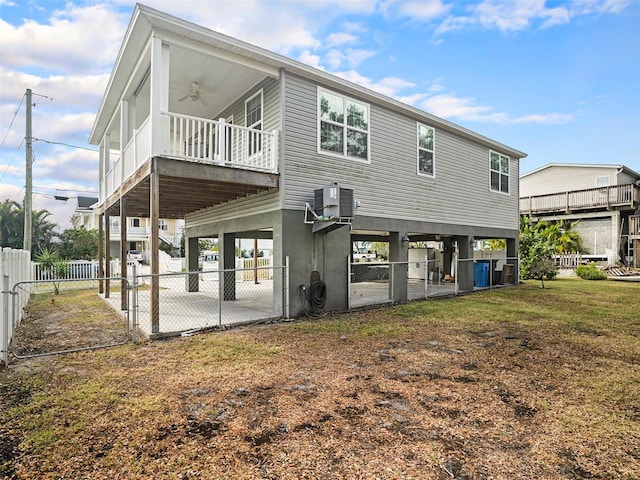 rear view of property featuring a carport, a yard, ceiling fan, and central air condition unit