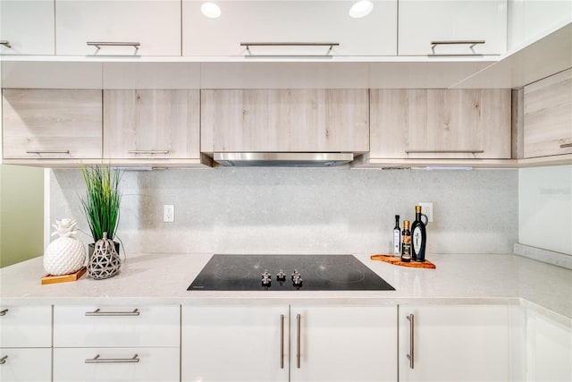 kitchen featuring black electric stovetop, backsplash, light stone counters, extractor fan, and white cabinets