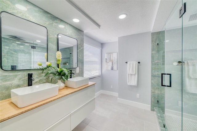 bathroom featuring tile patterned floors, walk in shower, a textured ceiling, vanity, and tile walls