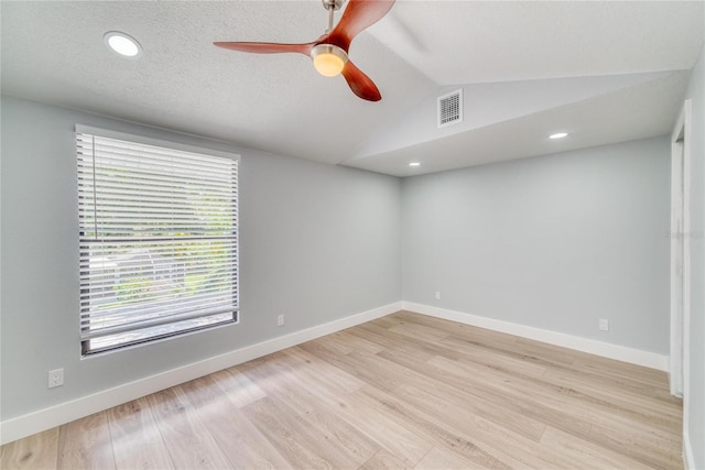 spare room featuring a textured ceiling, ceiling fan, light hardwood / wood-style flooring, and vaulted ceiling