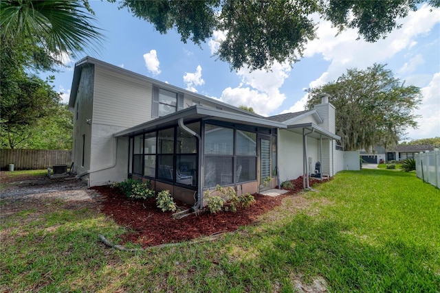 view of side of home with a sunroom and a lawn