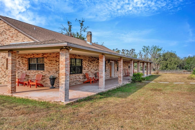 rear view of property featuring a yard, a patio, brick siding, and fence