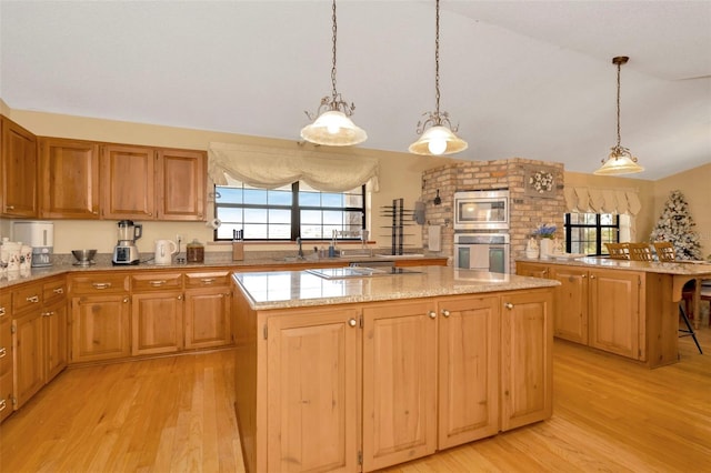 kitchen with light wood-type flooring, vaulted ceiling, stainless steel microwave, and a kitchen island