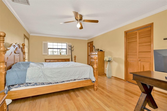 bedroom featuring ornamental molding, visible vents, a textured ceiling, and wood finished floors