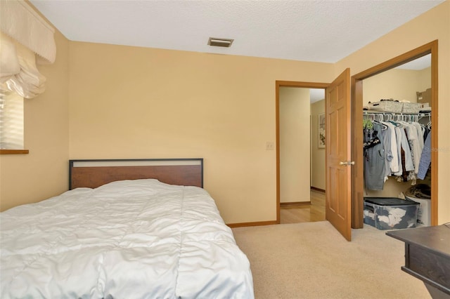 carpeted bedroom featuring a closet, visible vents, a textured ceiling, and baseboards