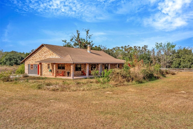 view of front of home with a patio, a front lawn, a chimney, and fence