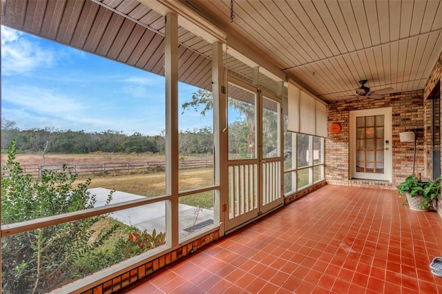 unfurnished sunroom with a healthy amount of sunlight, wood ceiling, and a ceiling fan