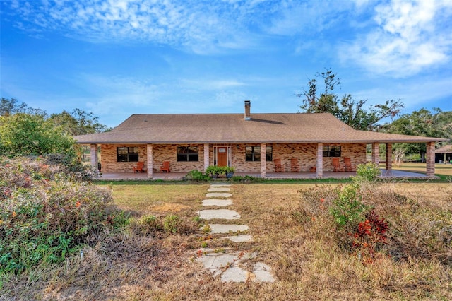 view of front of home with a patio area, a chimney, a front lawn, and brick siding