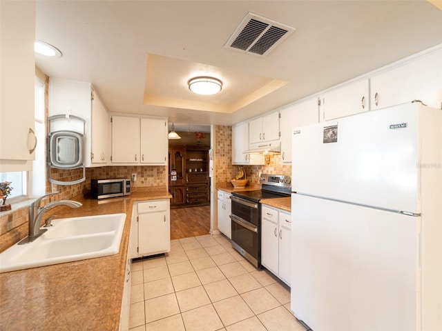 kitchen featuring white cabinets, stainless steel appliances, a raised ceiling, and sink