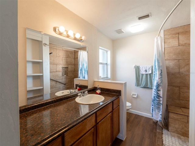 bathroom featuring wood-type flooring, vanity, toilet, and walk in shower