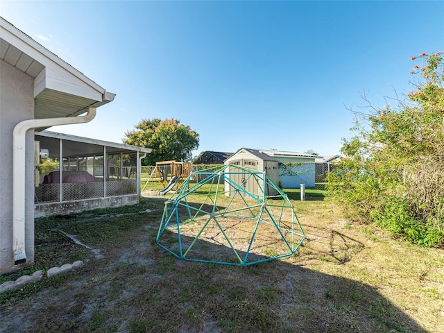 view of jungle gym with a sunroom, an outbuilding, and a yard