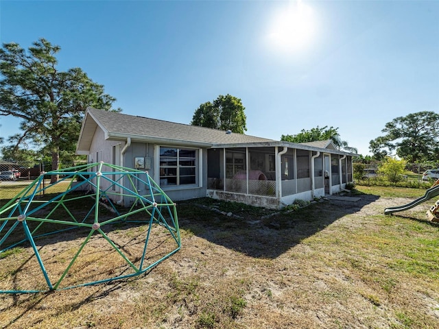 back of house featuring a yard, a playground, and a sunroom