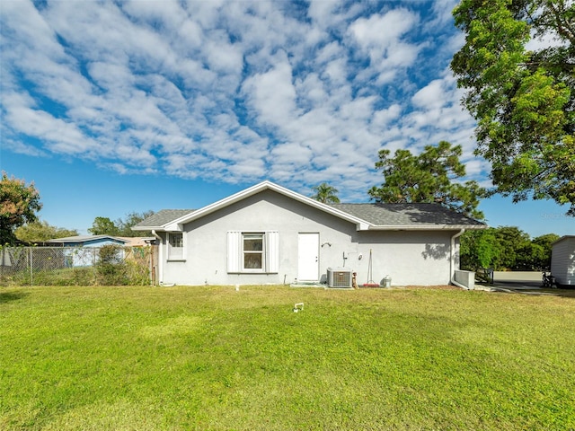 back of property with central AC unit and a lawn