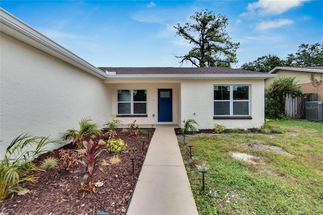 doorway to property featuring a yard and central AC unit