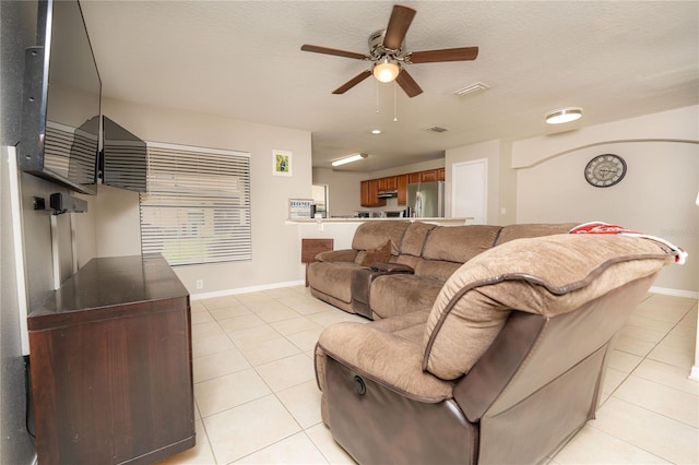 living room featuring ceiling fan, light tile patterned flooring, and a textured ceiling