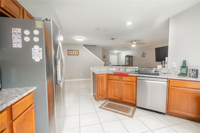 kitchen featuring ceiling fan, light tile patterned floors, appliances with stainless steel finishes, light stone counters, and kitchen peninsula