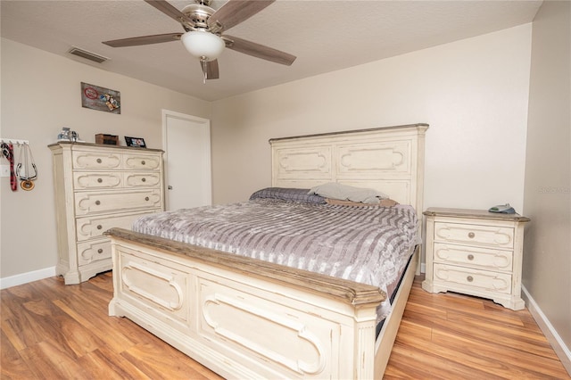 bedroom with ceiling fan, light wood-type flooring, and a textured ceiling