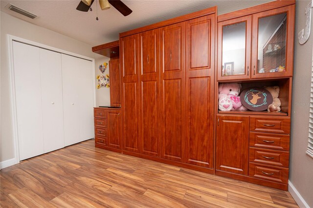 unfurnished bedroom with a closet, ceiling fan, light hardwood / wood-style flooring, and a textured ceiling