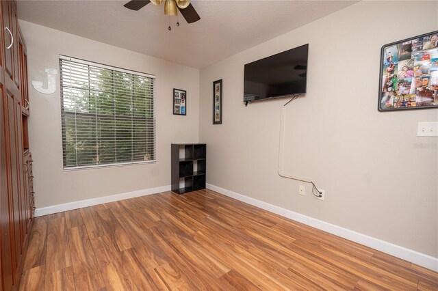 empty room featuring ceiling fan, wood-type flooring, and a textured ceiling