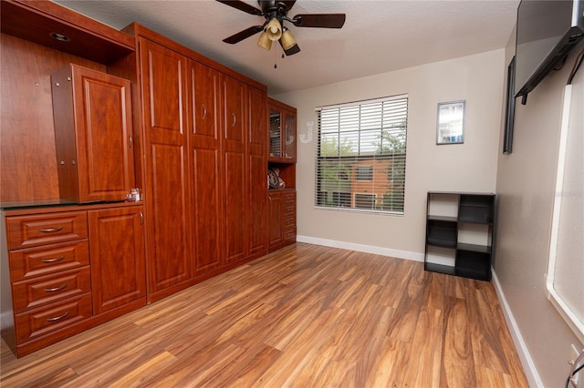 unfurnished bedroom with ceiling fan, a closet, light hardwood / wood-style floors, and a textured ceiling