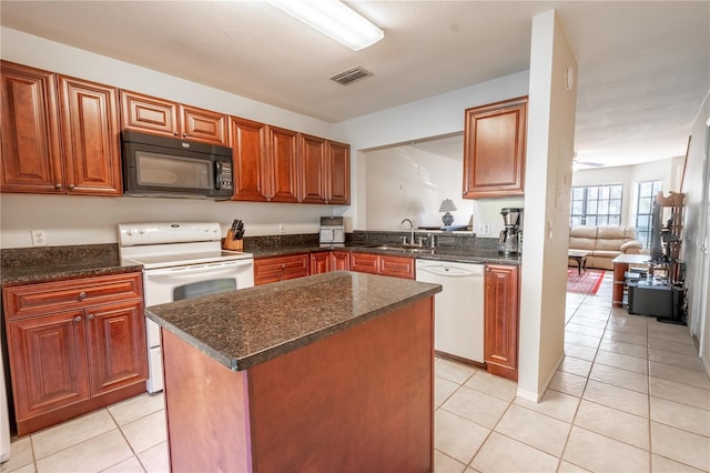 kitchen featuring white appliances, sink, light tile patterned floors, dark stone countertops, and a center island