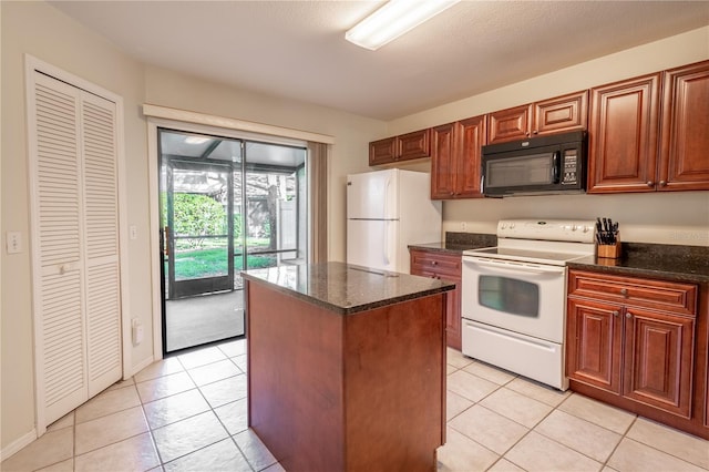 kitchen featuring light tile patterned floors, white appliances, a kitchen island, and dark stone counters