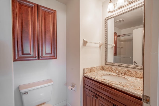 bathroom featuring vanity, toilet, and a shower with shower door