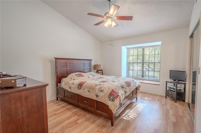 bedroom with vaulted ceiling, light hardwood / wood-style flooring, ceiling fan, a textured ceiling, and a closet