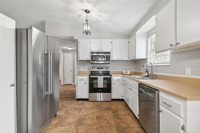 kitchen featuring lofted ceiling, sink, decorative light fixtures, white cabinetry, and stainless steel appliances