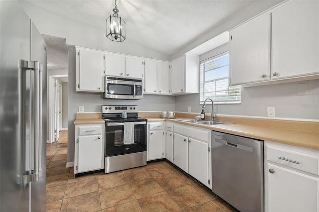 kitchen featuring white cabinetry, sink, pendant lighting, vaulted ceiling, and appliances with stainless steel finishes