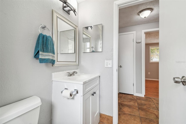 bathroom featuring tile patterned floors, vanity, toilet, and a textured ceiling