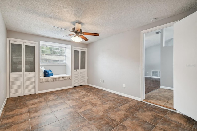 empty room with ceiling fan and a textured ceiling