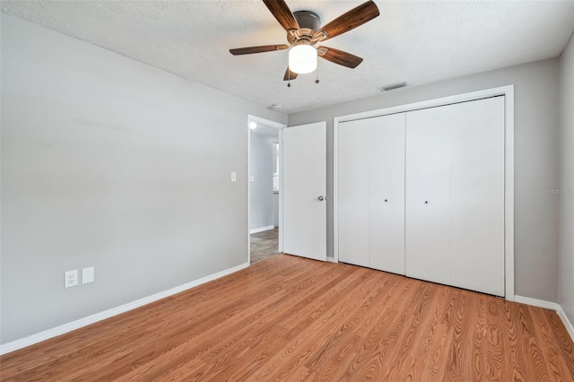 unfurnished bedroom featuring ceiling fan, a closet, light hardwood / wood-style floors, and a textured ceiling