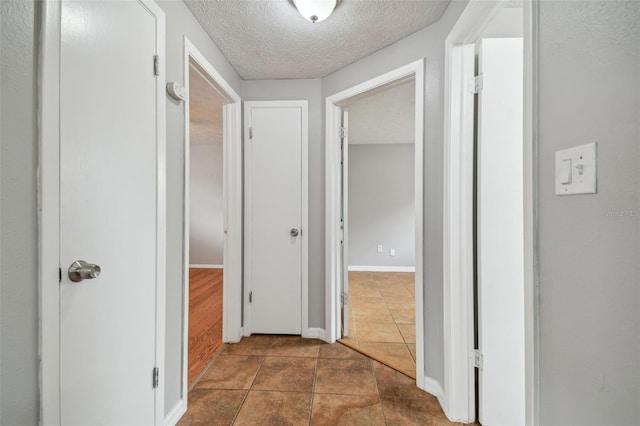 corridor featuring dark tile patterned floors and a textured ceiling