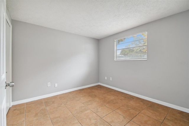 tiled spare room with a textured ceiling