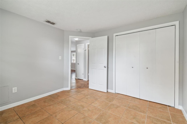 unfurnished bedroom with a closet, light tile patterned flooring, and a textured ceiling